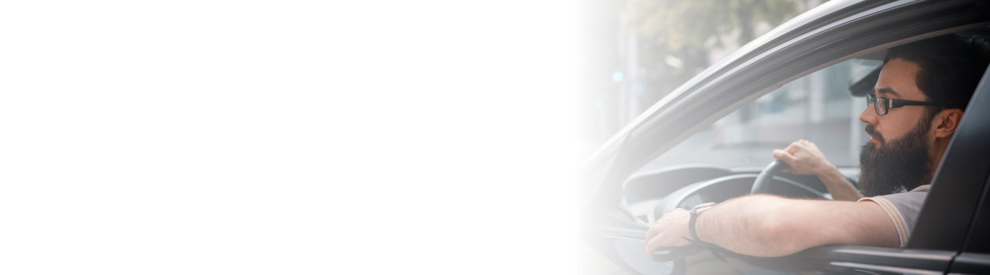 Hombre dentro de su vehículo, tranquilo, transitando por la ciudad, después de adquirir un Seguro Complementario automotriz Banorte.