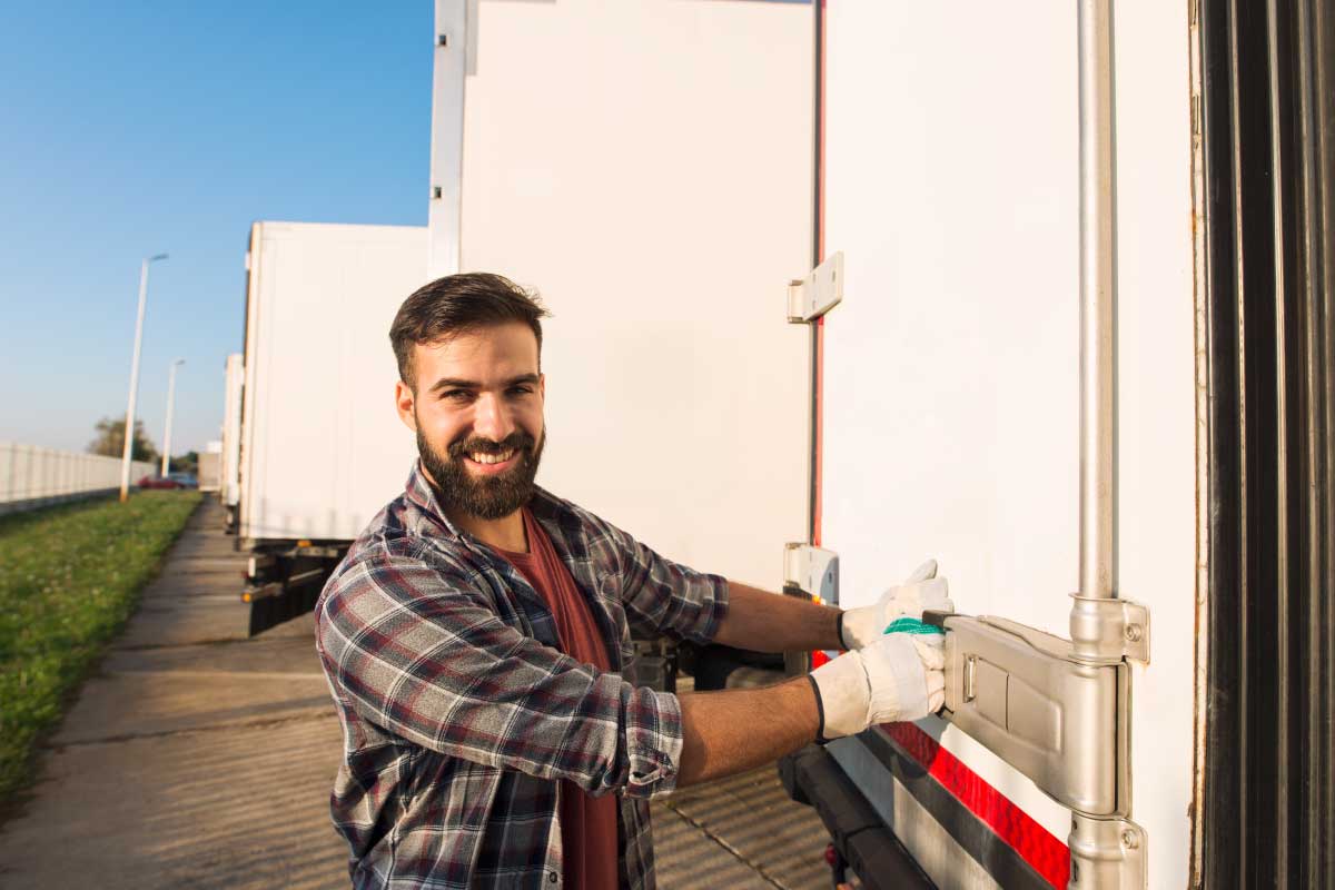 Hombre joven asegurando las puertas de un vehículo que cuenta con la protección de una póliza de seguros para camiones.